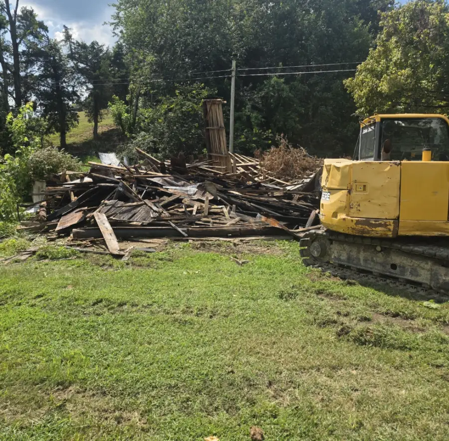 Excavator beside the debris of a torn-down barn