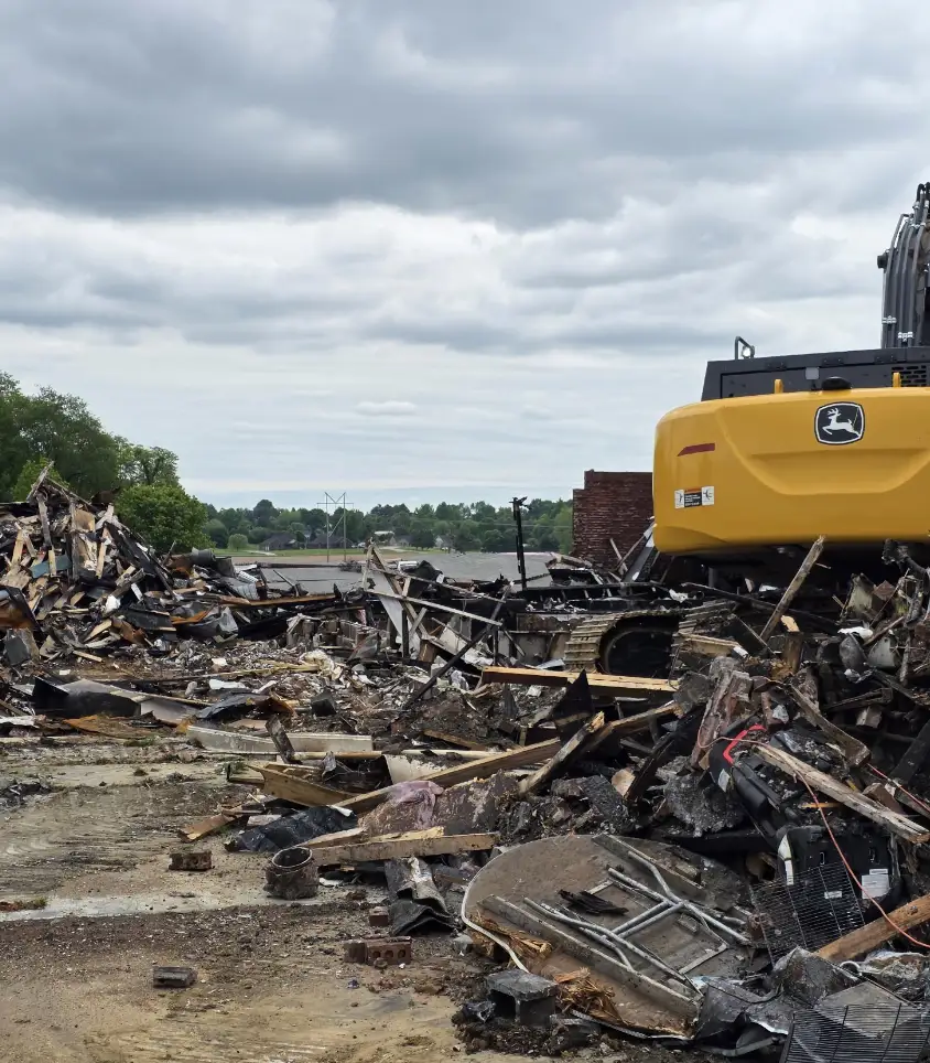 Excavator working over a pile of demolition debris