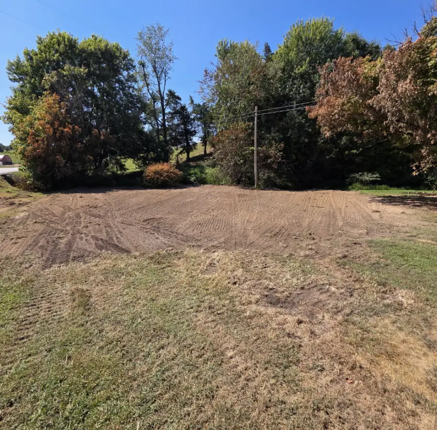 Graded lot with fall trees behind it