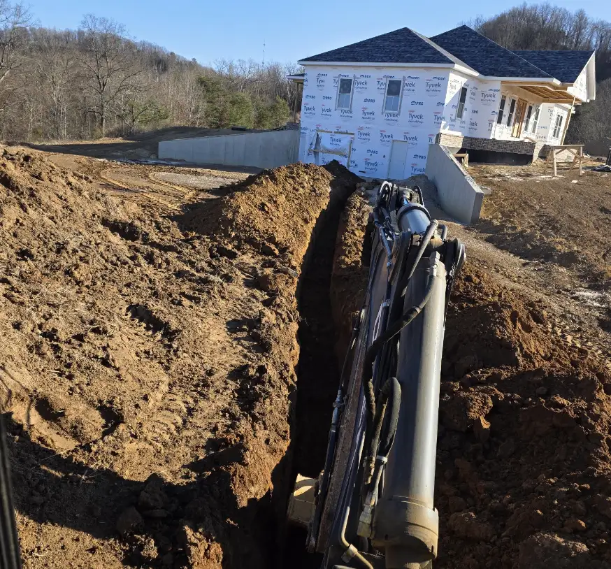 Excavator trenching toward a new house