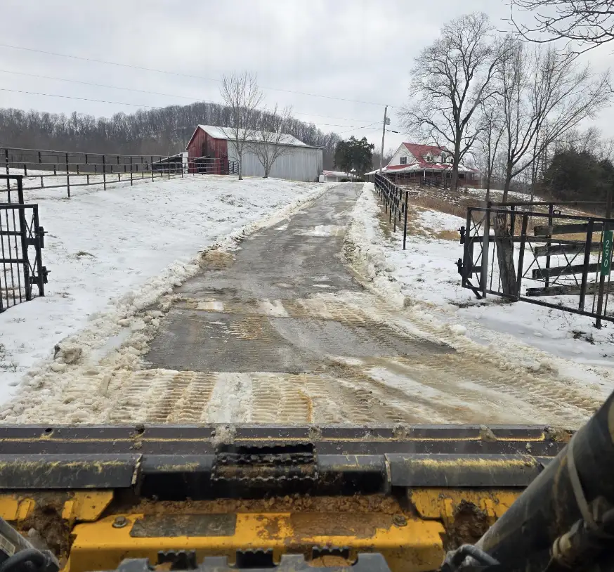 Farm lane between board fences seen from a skid steer on a winter day